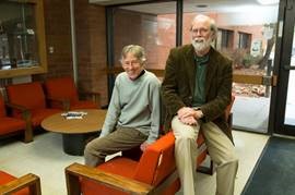 Two men sit on orange-upholstered furniture in the Law School lounge