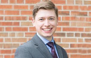 Jonathan Brown smiles in portrait in front of brick building